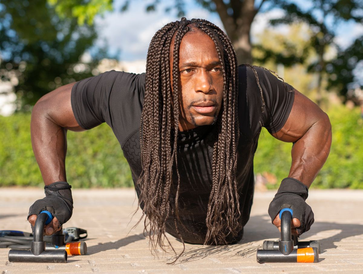 Man doing push-ups outdoors using a pair of push-up bars