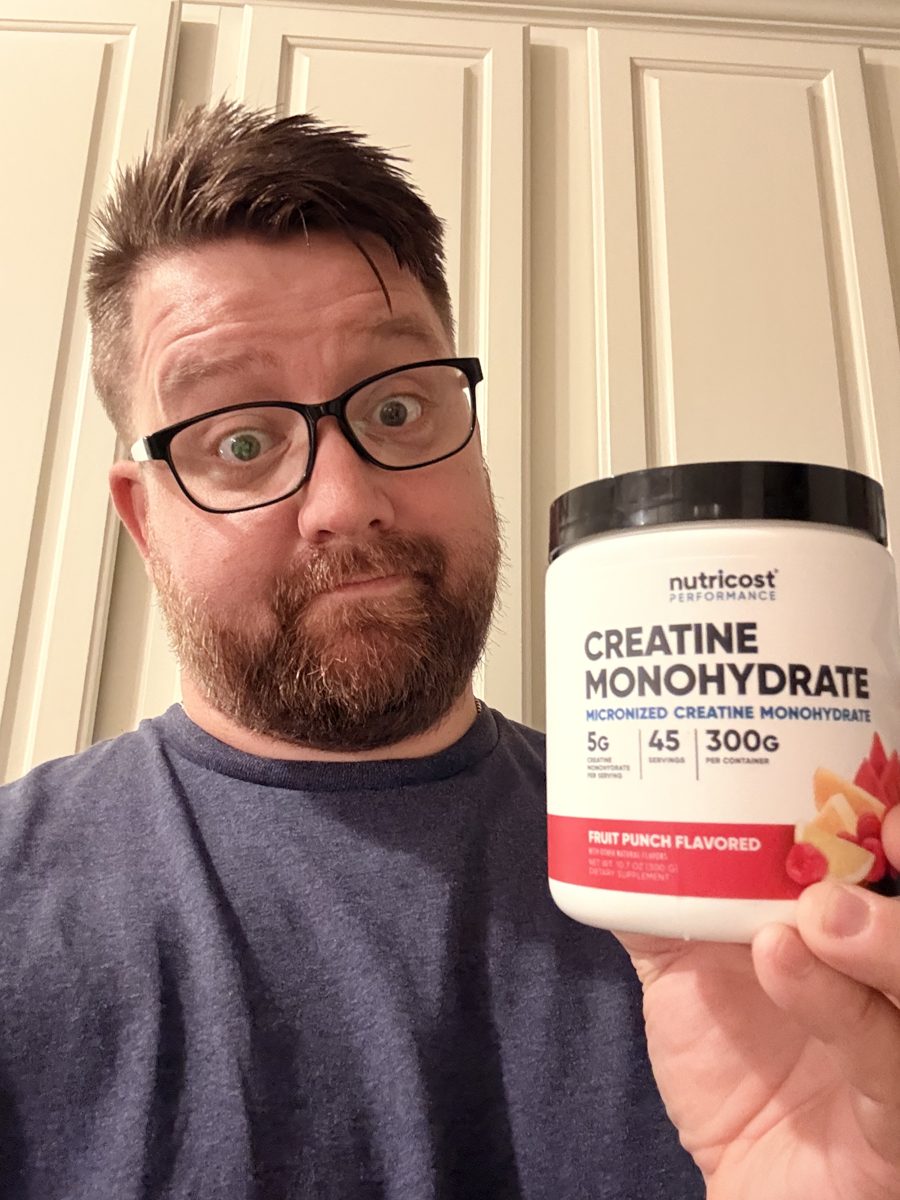 Brett holding his tub of Nutricost Fruit Punch creatine monohydrate